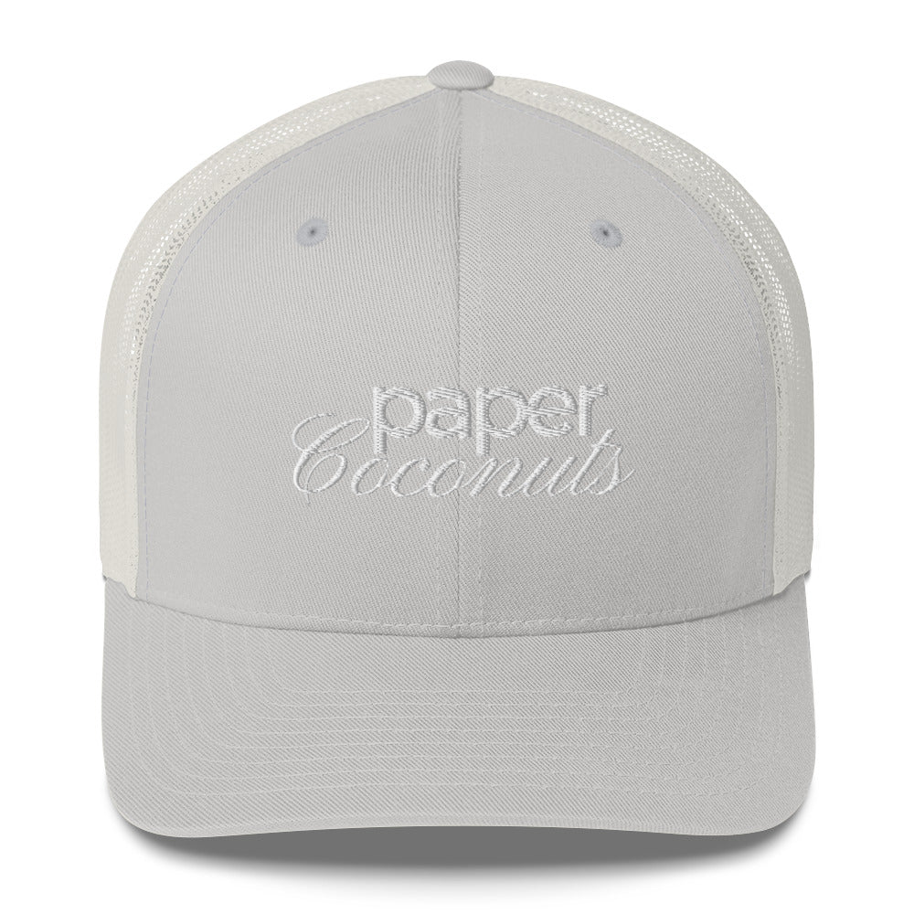 Silver trucker hat with "Paper Coconuts" logo in stylized embroidered white text. The cap features a black front panel and white mesh back, showcasing a modern brand design .