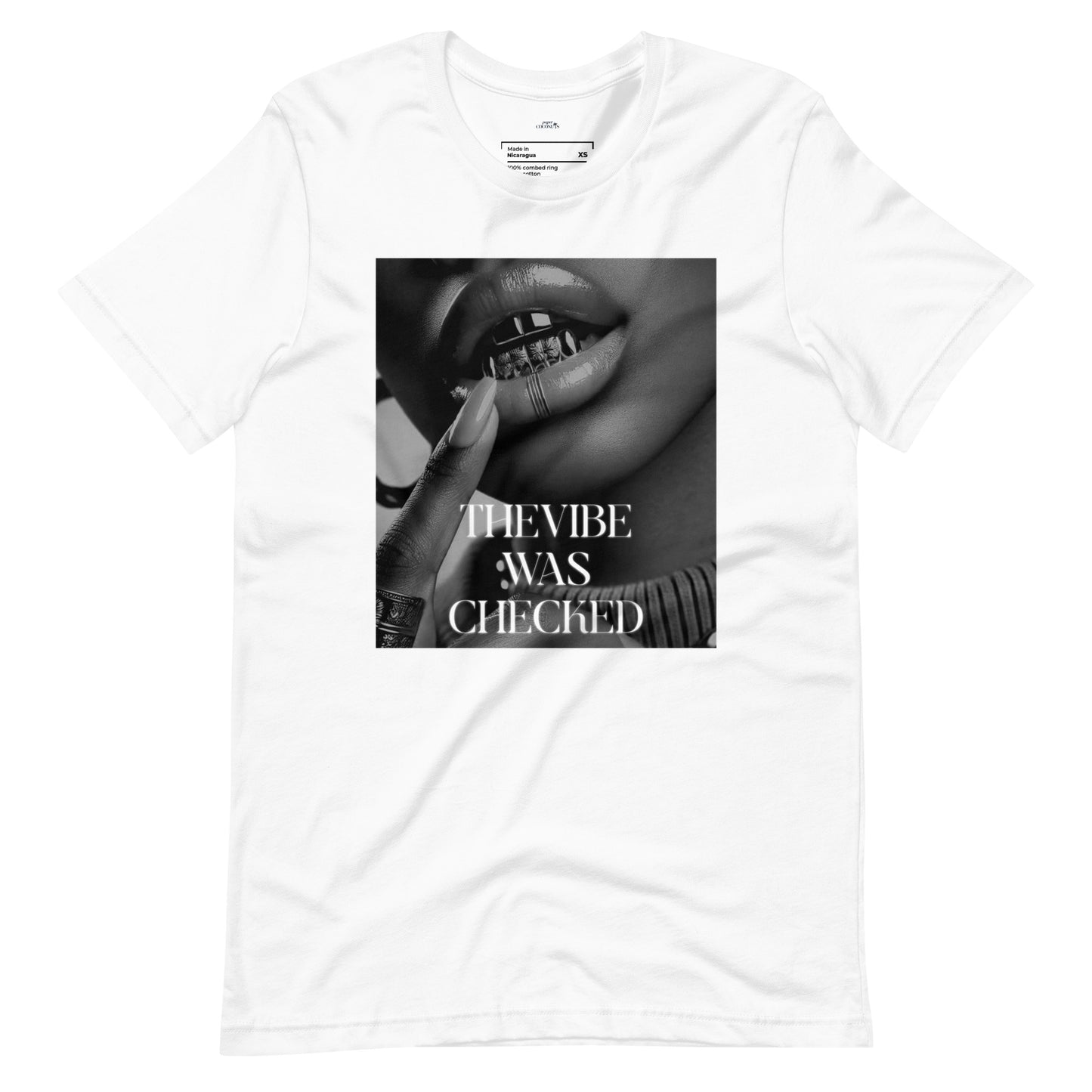 White graphic t-shirt featuring a bold black-and-white print of lips with a grill and the phrase "THE VIBE WAS CHECKED.