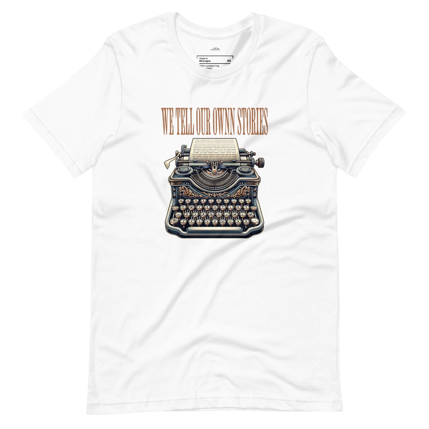 White t-shirt featuring a vintage typewriter graphic and the phrase "WE TELL OUR OWN STORIES" in bold lettering.