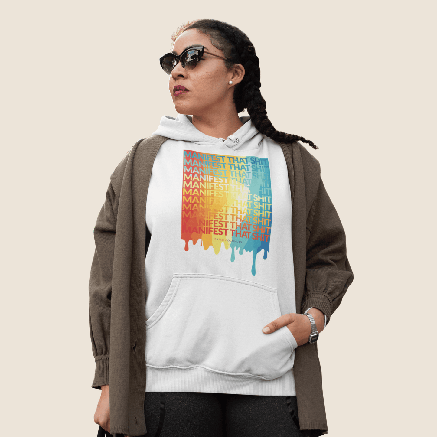 Person wearing a white hoodie with colorful text design on a beige background