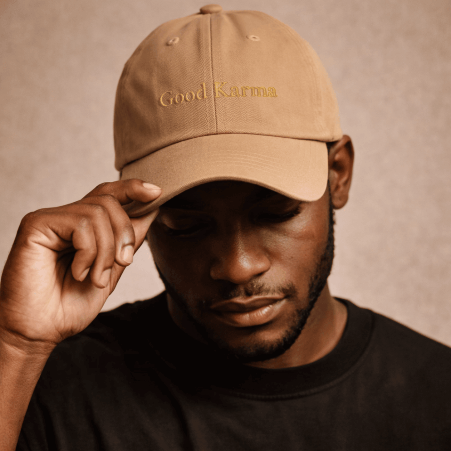Man wearing a tan cap with 'Good Karma' text on a beige background