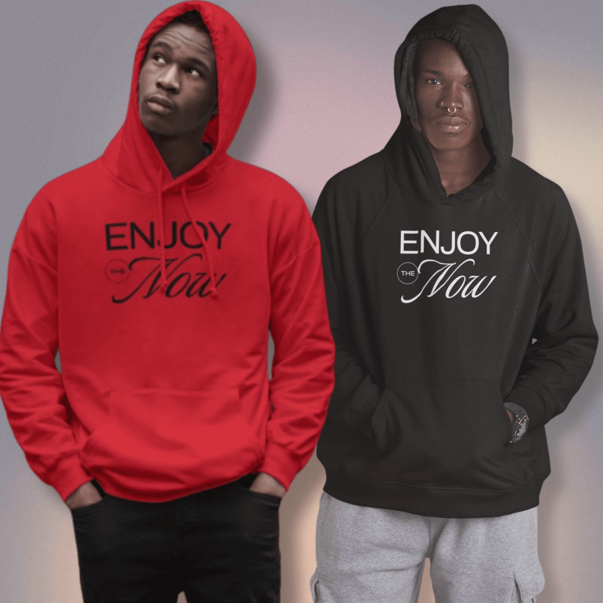 Two men wearing Paper Coconuts 'Enjoy The Now' hoodies, one in bold red with black text and the other in black with white text.